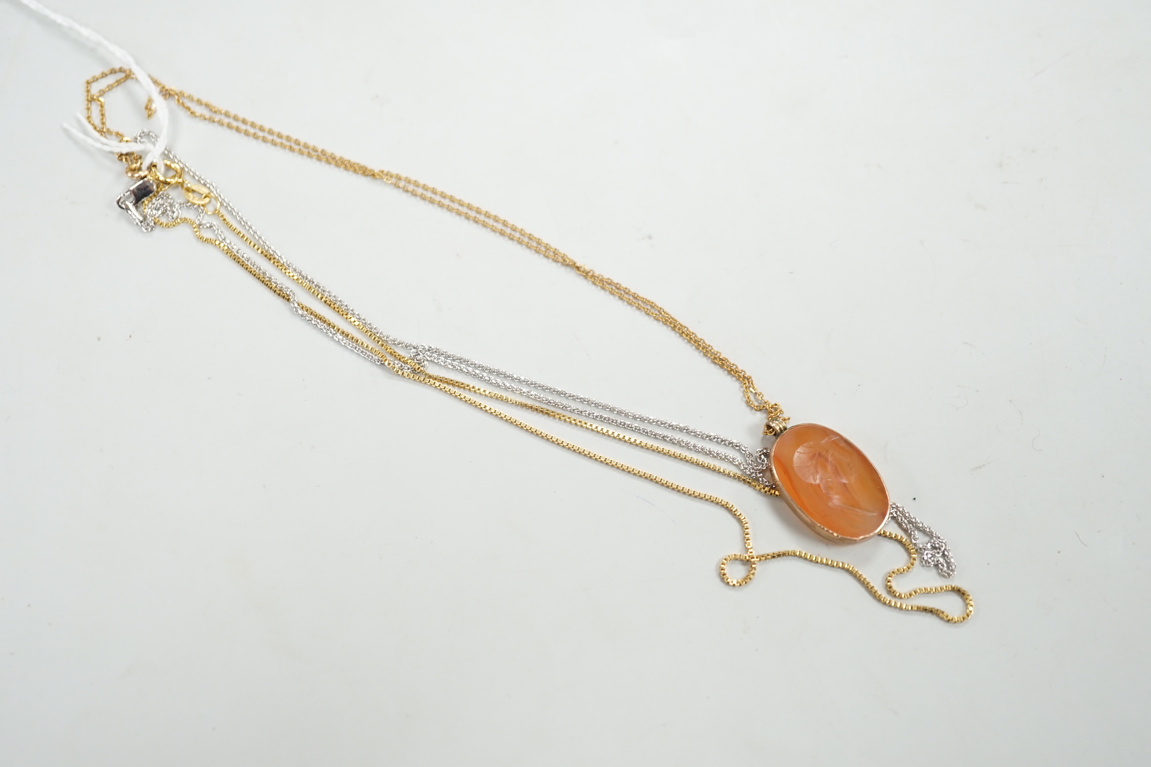 A yellow metal mounted oval intaglio carnelian stone, carved with the bust of gentleman to sinister, 23mm on a 9ct fine link, 37cm and two 9ct gold chains. including white gold, gross weight 8.7 grams.